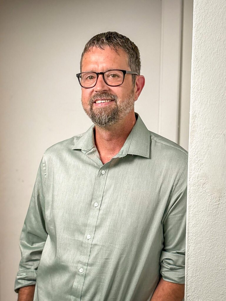 Mike Dolinsek, personal development coach and NLP practitioner, standing against a white wall